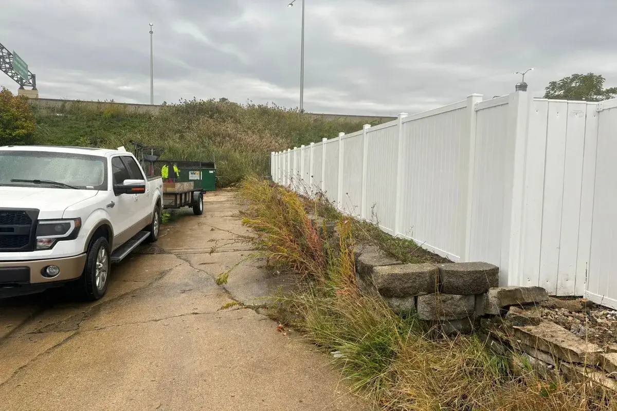 White vinyl fence screening a gravel drive at a commercial lot