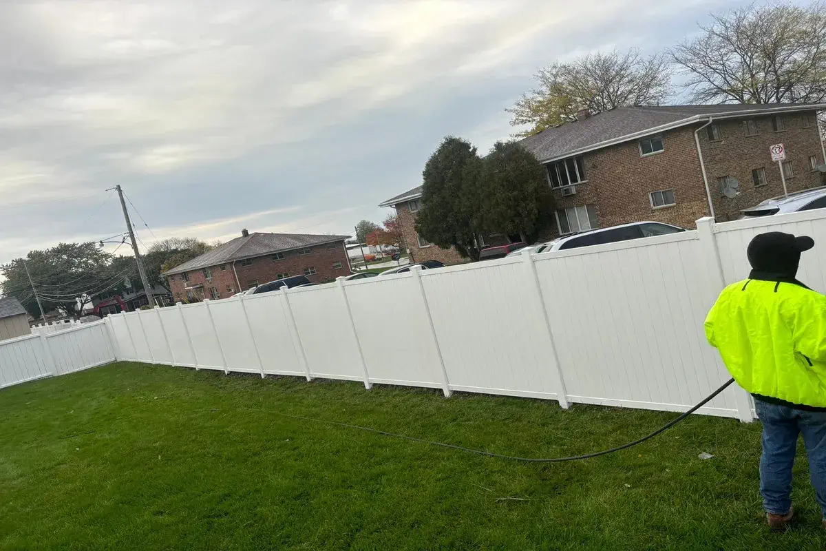 White vinyl fence stretching along an open lawn