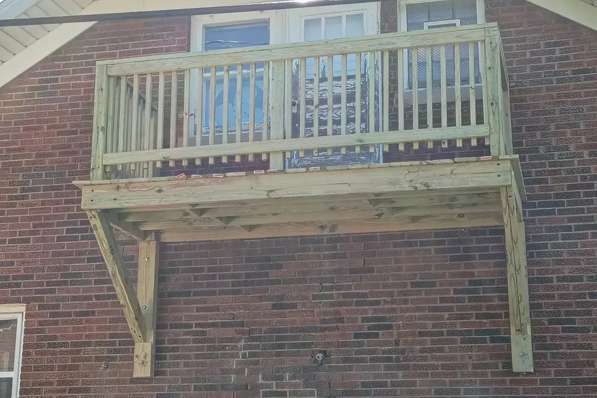 Second level porch framed against a brick wall