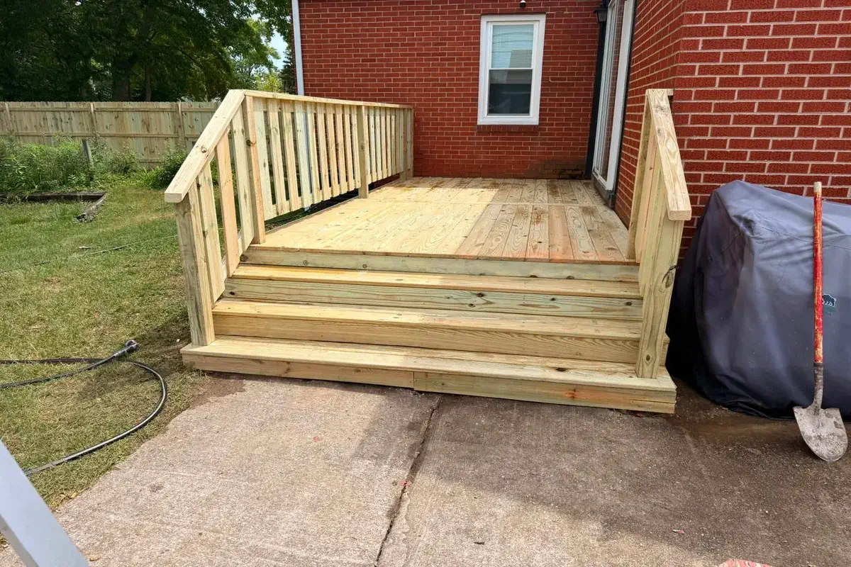 Wood deck with wide stairs stepping down to a driveway