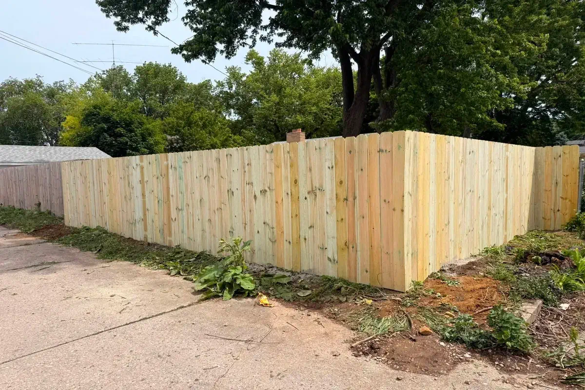 Newly built wood privacy fence turning a corner in a cleared yard